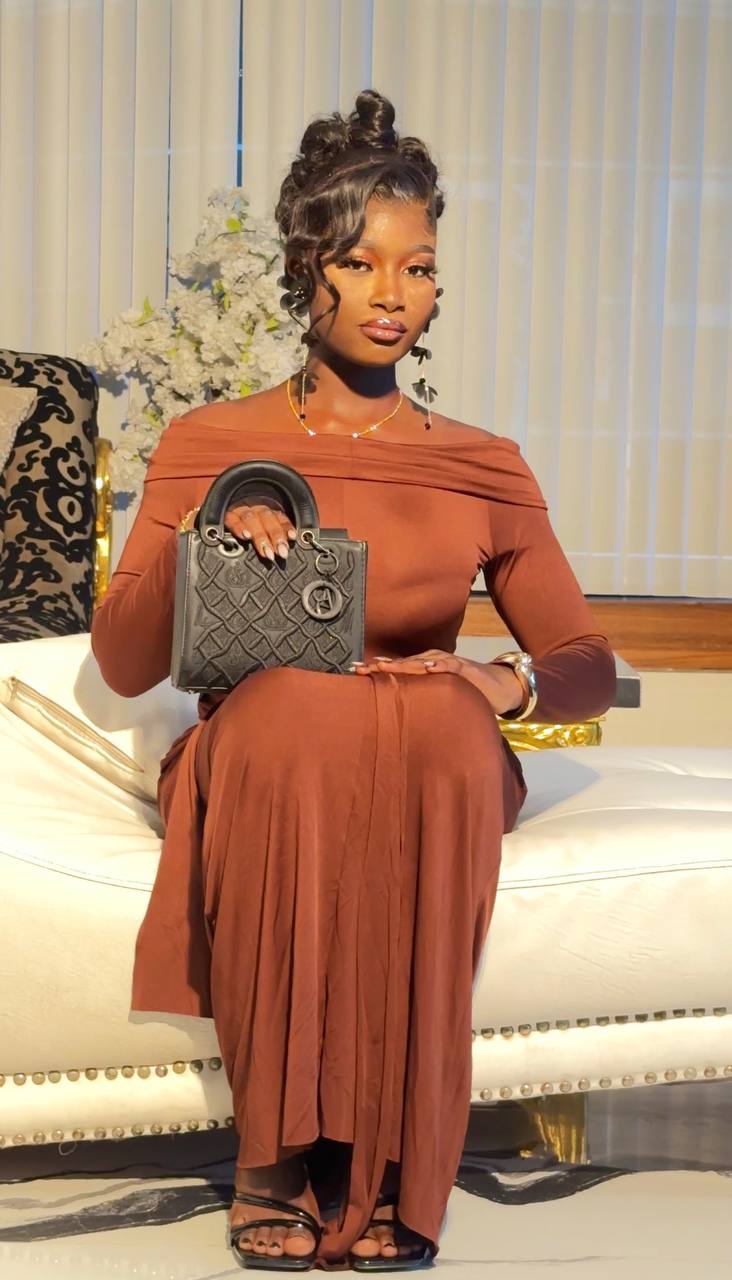 Woman in brown dress with soft glam makeup seated on white sofa